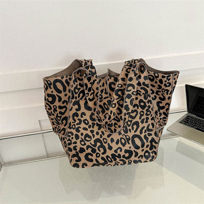 Leopard print tote bag on a glass surface with a laptop in the background