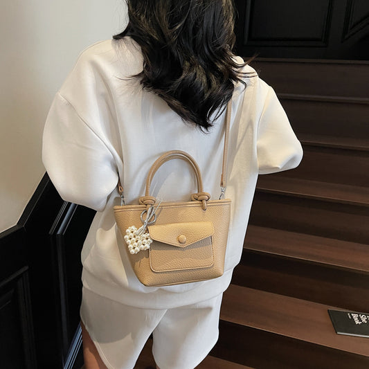 Person wearing a beige handbag with a pearl charm on a staircase