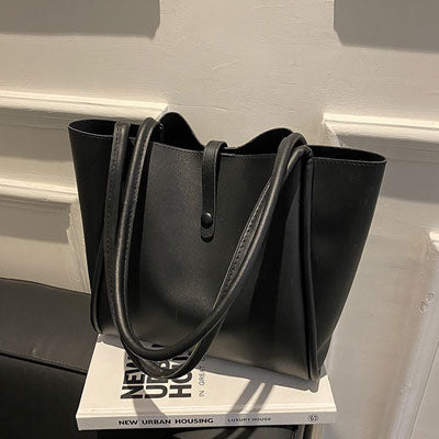 Black tote bag on a white surface with a blurred background