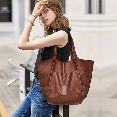 Woman holding a brown leather tote bag in an urban setting