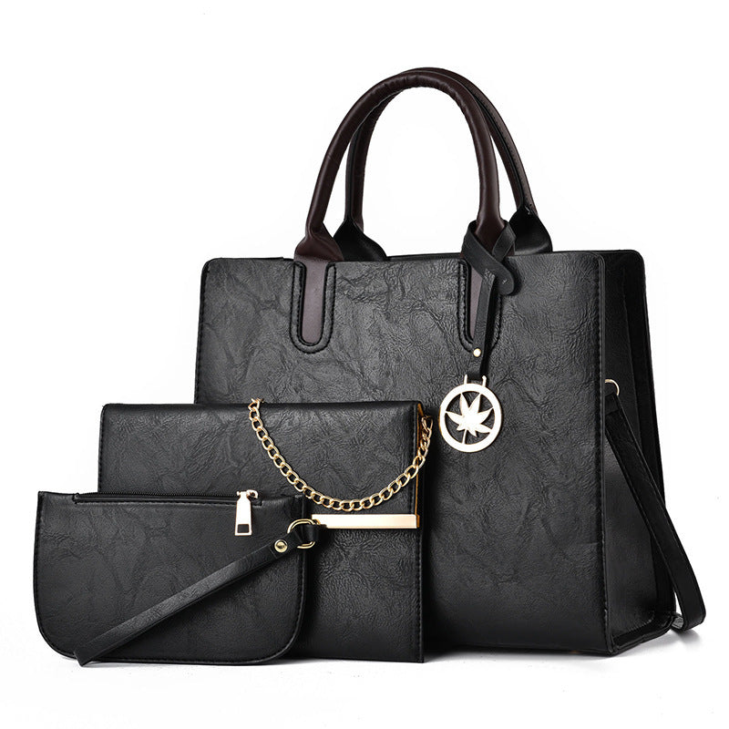 Black handbag set with a smaller pouch and chain detail on a white background