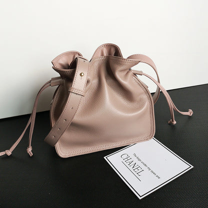 Flat lay of square vertical cowhide pull-belt bucket bag with props